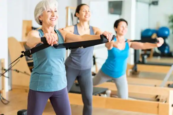 Toning Arms After 60: Empowering Womens Fitness Through Effective Weight Training 2 older woman doing weight training Solihull and resistance in the gym to tone upper arms